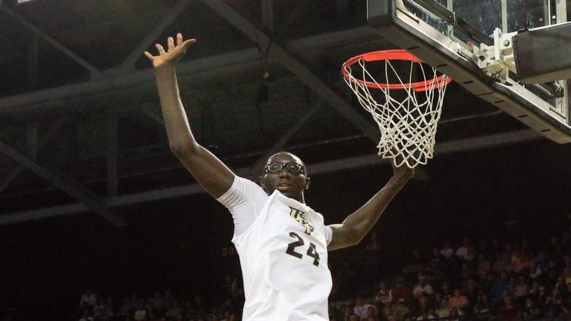 Central Florida center Tacko Fall towers over Cincinnati’s Gary Clark during a game in February. Fall will be back at UCF after testing the NBA waters this spring.