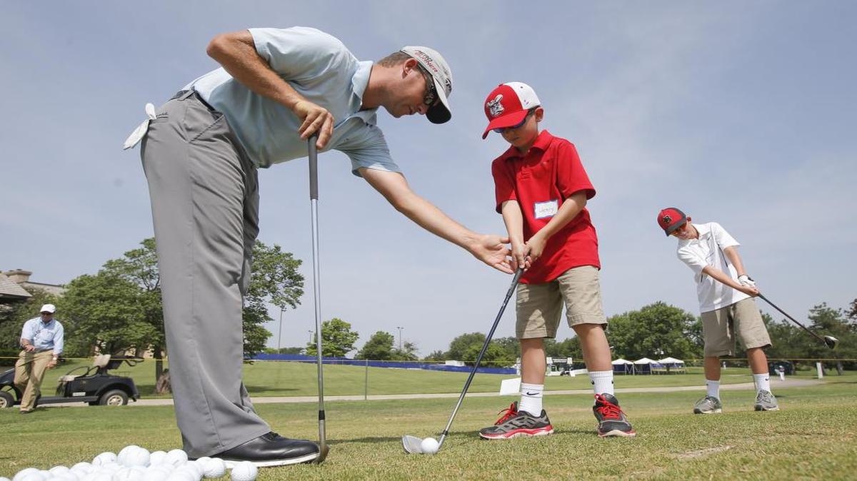 
Kyle Thompson offers instructions to Henry Schmidt during the Kids Golf Clinic at Crestview Country Club on Tuesday. The clinic is part of this week's Air Capital Classic golf tournament. 
