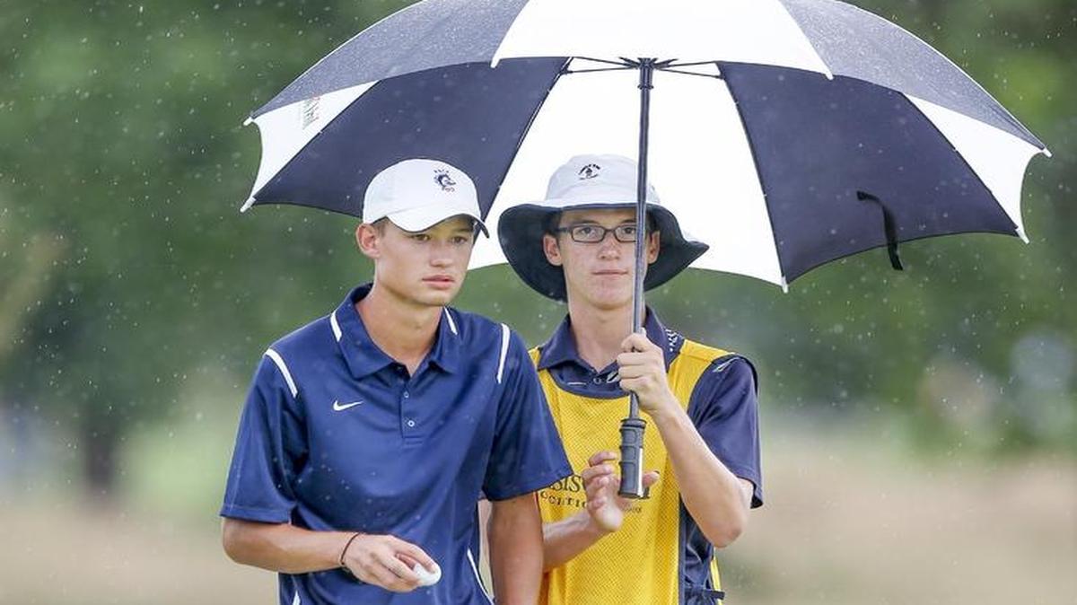 
Austin Shanks, left, gets a little help from his friend and caddy Kellen Marshall keeping dry during the first day of the Kansas Amateur on Tuesday. 
