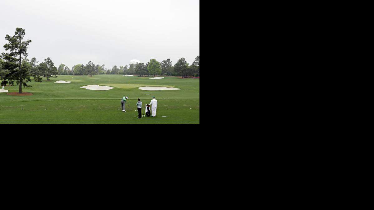 
Tiger Woods is watched by his coach Chris Como as he hits on the driving range during a practice round for the Masters golf tournament Wednesday, April 8, 2015, in Augusta, Ga. 
