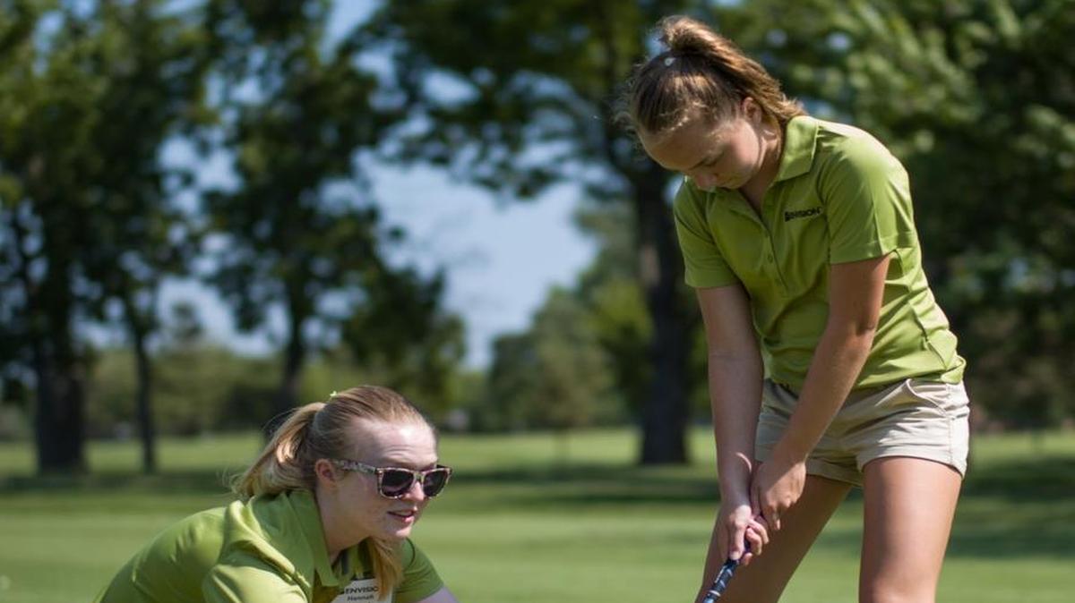 Hannah Whipple, a volunteer with Envision Wichita, helps Julia McLeod line up a shot at Crestview Country Club during the Marge Page Junior ProAm on Tuesday afternoon.