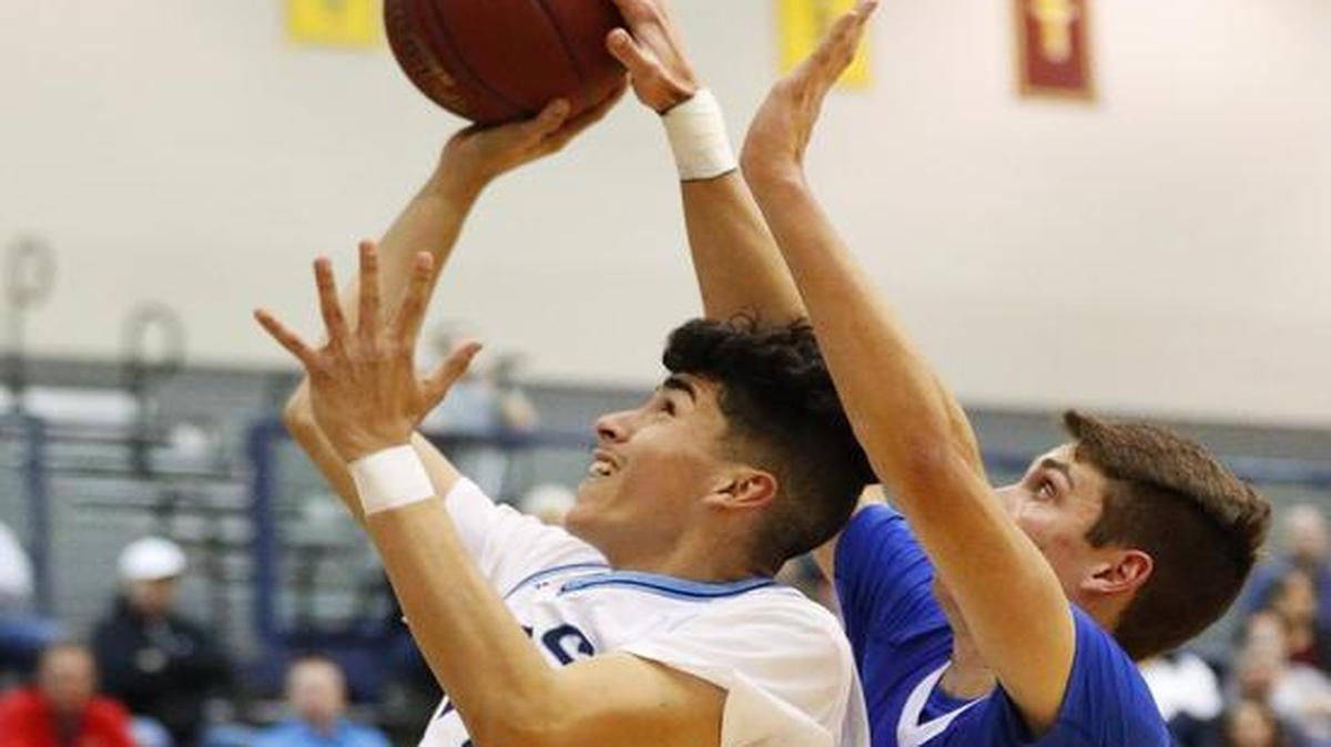 Wichita East’s Emilio Valentin, left, shoots as Kapaun’s JT Bell defends in the second quarter Tuesday night.