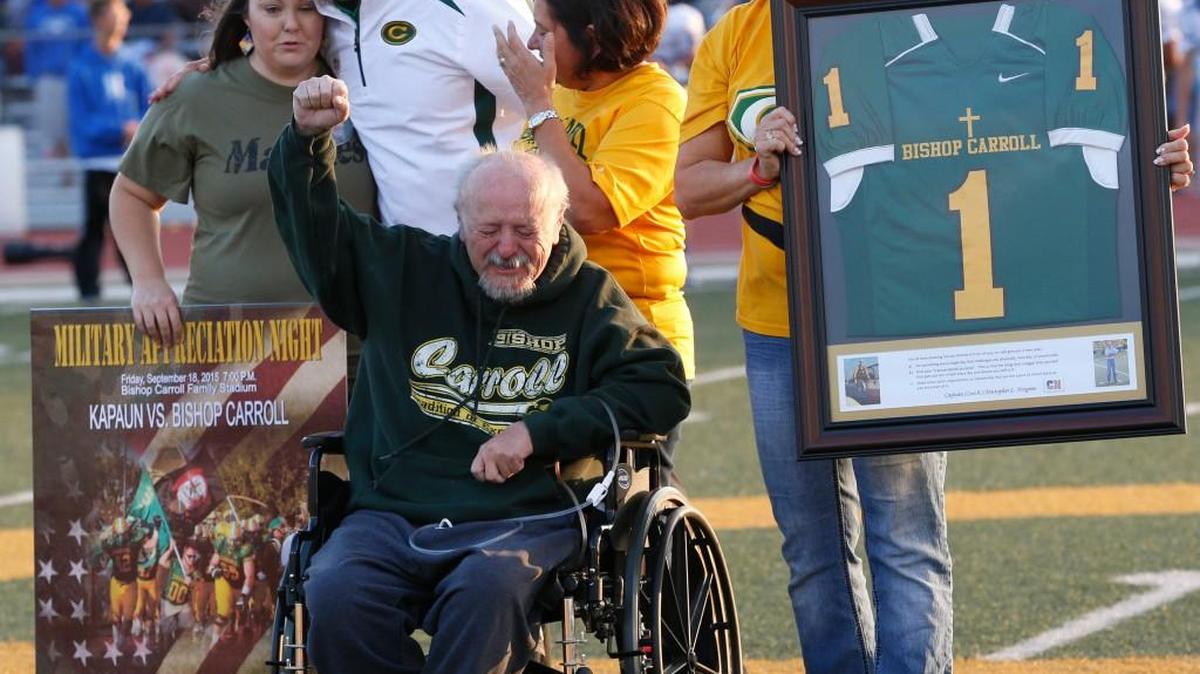Ron Norgren pumps his fist into the air as his son Capt. Chris Norgren is remembered during Military Appreciation night at Carroll earlier this fall. Holding a framed jersey is Terri Norgren, Chris’ mom.