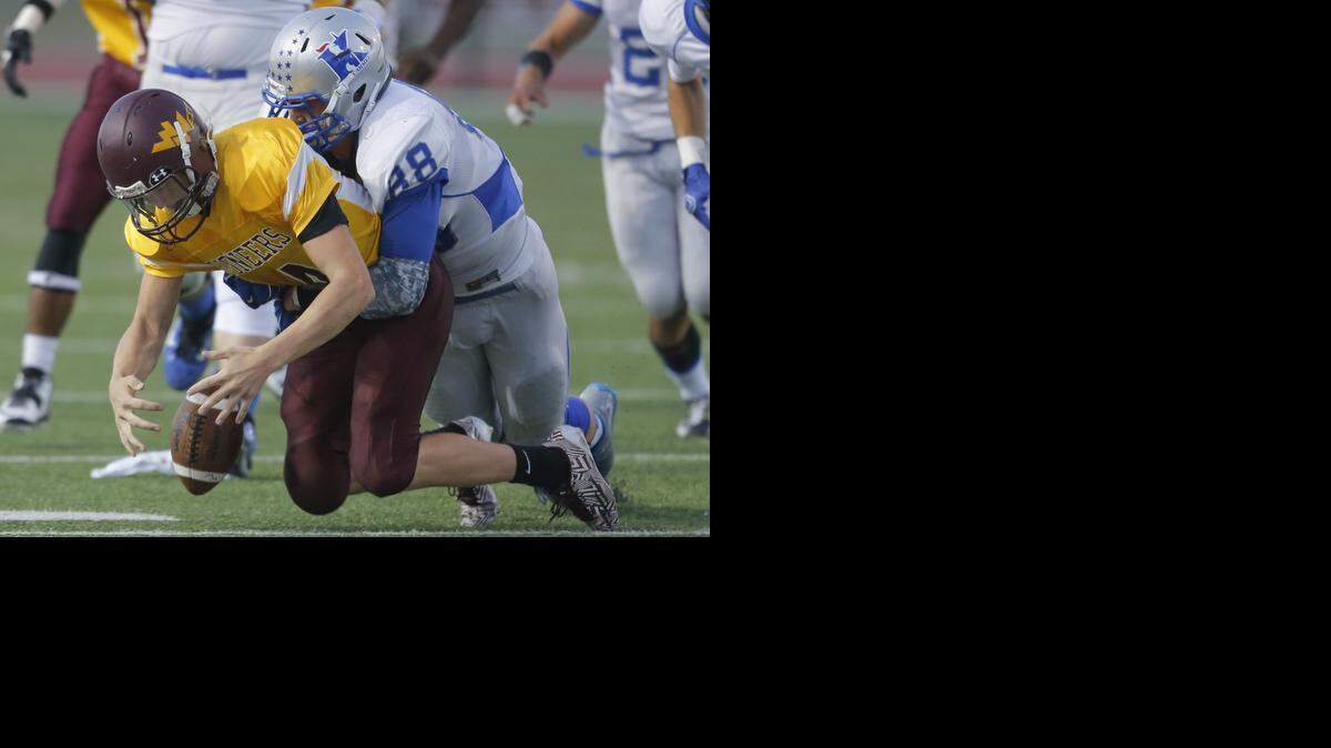 
West High quarterback Chaz Capps fumbles the ball after being hit by Kapaun defender Michael Lickteig during the first half of their game at Heights on Friday night.
