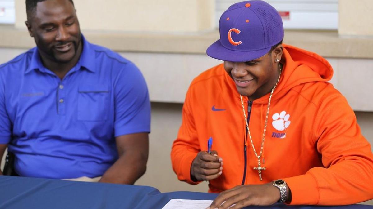 East High football player Xavier Kelly signs a letter of intent to play for Clemson University. At left is his father, Will Kelly.