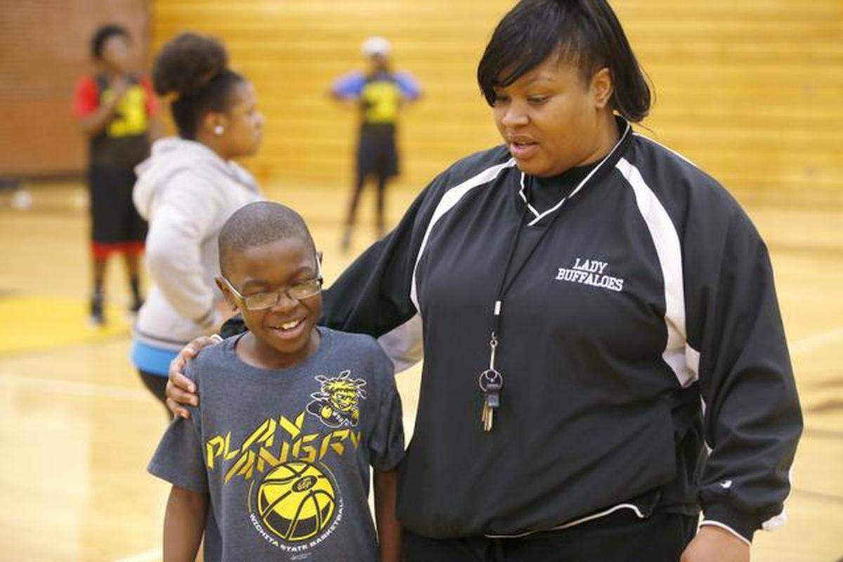 Southeast High School basketball coach LaToya Randle talks to her son, Julian, during a recent practice. Julian has a rare autoimmune disease and cannot play basketball because of how sick he is, but he loves to be around the game and around the girls.