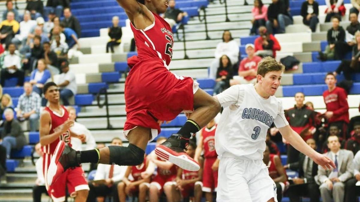 Heights' Aaron Williams, center, gets fouled by Kapaun's Chris Meitzner as he drives to the basket in the fourth quarter at Kapaun Mt. Carmel High Friday night.