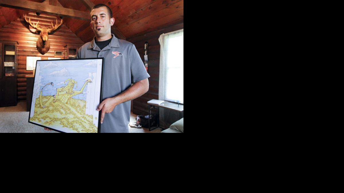 
Augusta football coach Jason Filbeck with one of the drawing he's done of a monster made from school supplies at his home.
