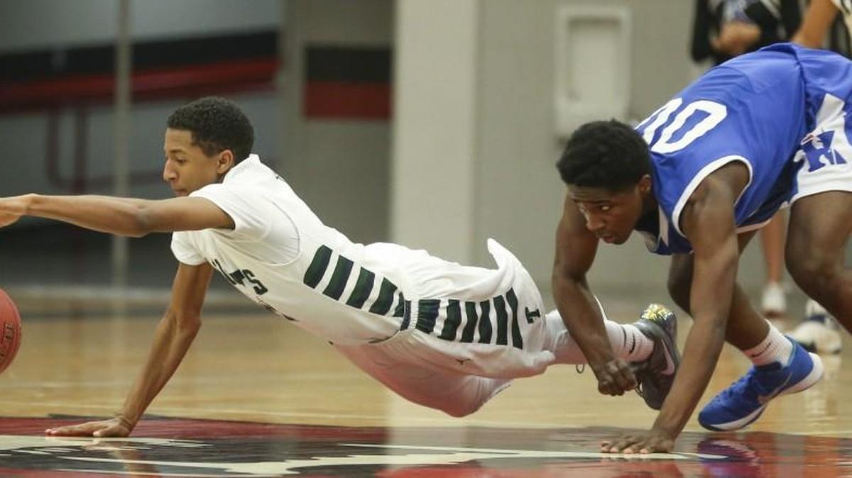 Trinity's Jarrett Counts dives for a loose ball in front of Kapaun’s Mark Hutton during the second quarter of their semifinal game of the Bluestem Classic in El Dorado on Friday night.