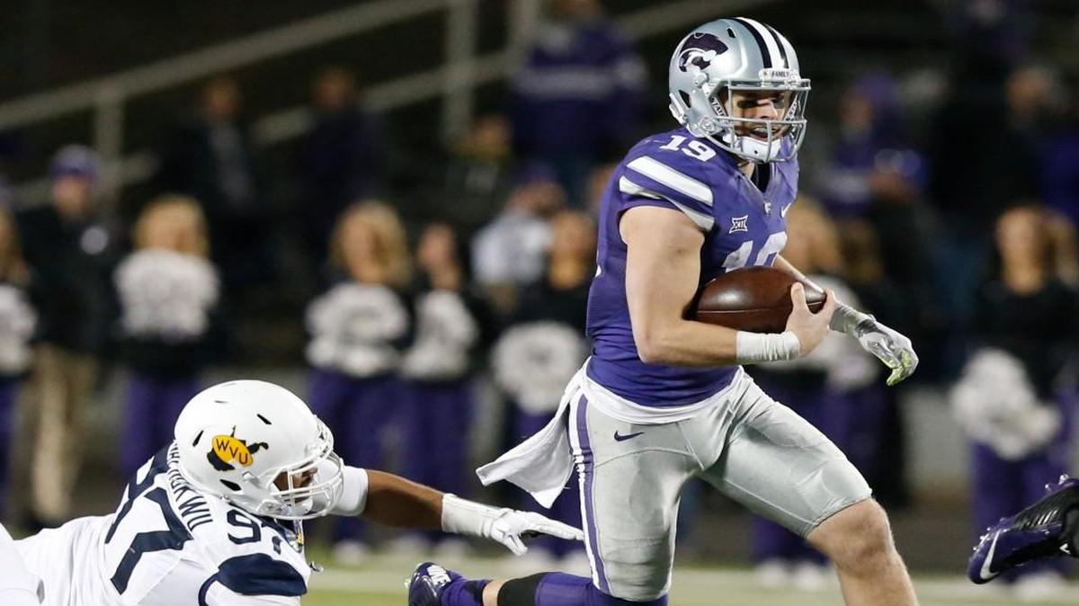 Kansas State quarterback Kody Cook slips past West Virginia defensive lineman Noble Nwachukwu during the final game of the regular season.