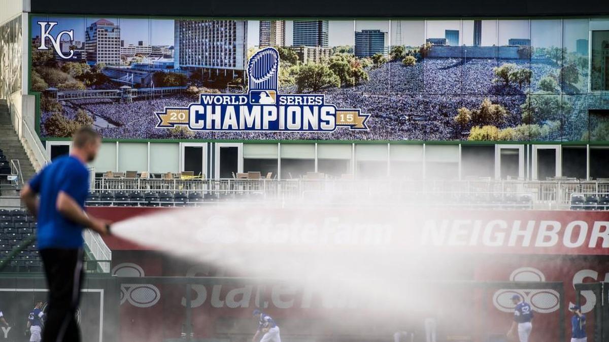 Kauffman Stadium’s grounds crew wets the field Tuesday before the start of the University of Missouri-Saint Louis University game. A new mural installed at the stadium features a photo of the crowds that attended the downtown Kansas City parade after the Royals won the World Series.
