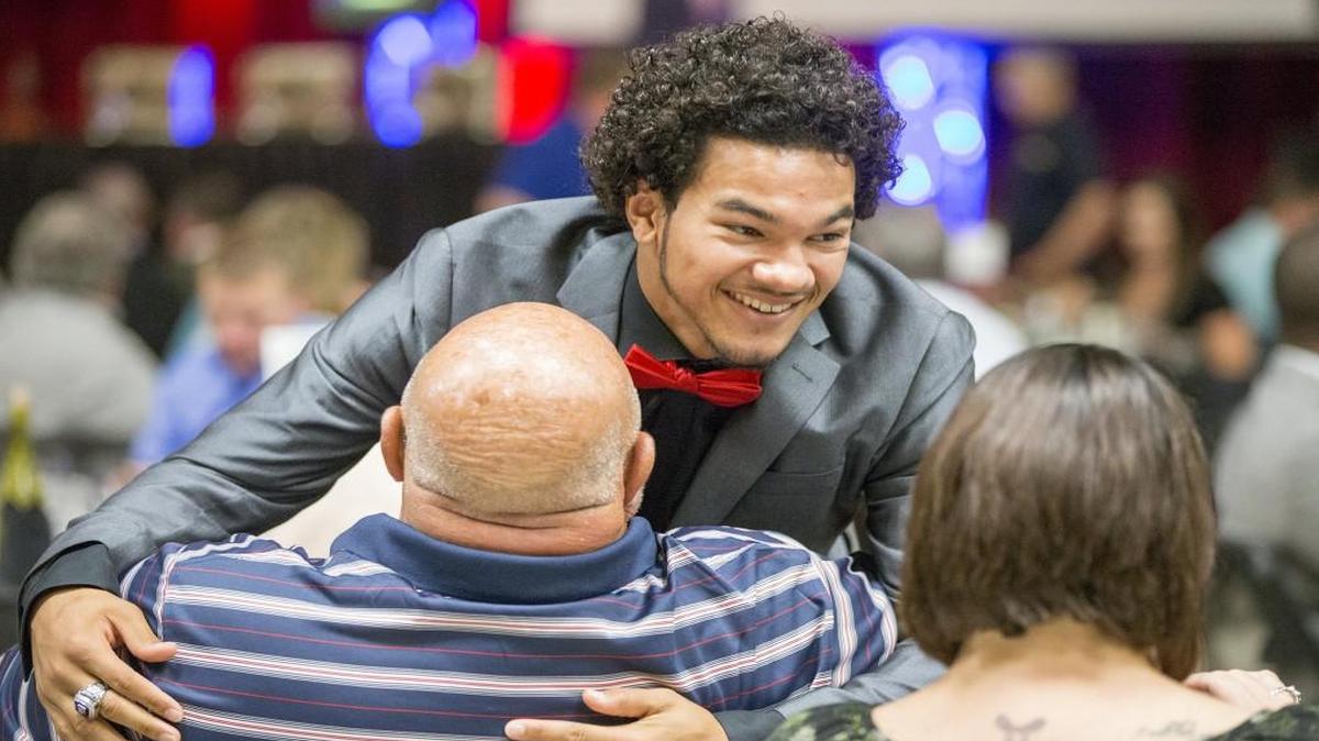 Heights athlete Creighton Sanders gets a hug from his grandfather Jim Schneiter after receiving the Barry Sanders High School Male Athlete of the Year award at the Greater Wichita Sports Banquet on Thursday at Century II.