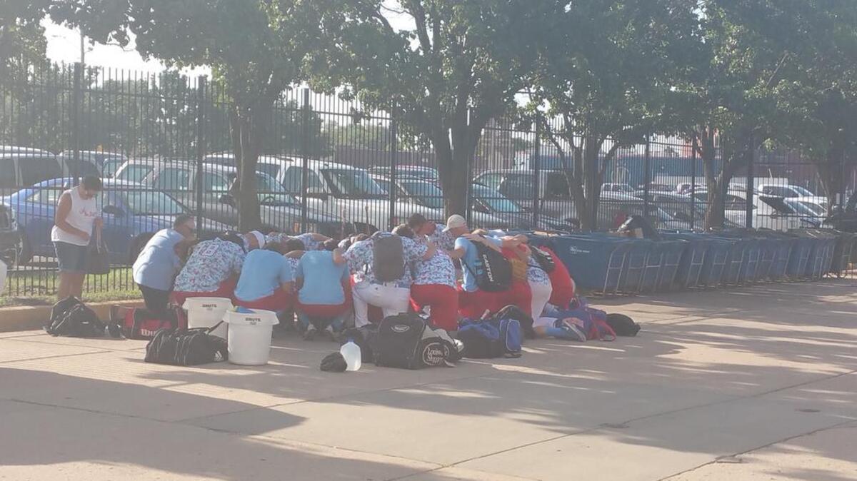 
Liberal Bee Jays players huddle for a prayer after their game Saturday. Their 9-year-old bat boy, Kaiser Carlile, was injured when he was hit in the head by the follow-through of a swing near the on-deck circle.
