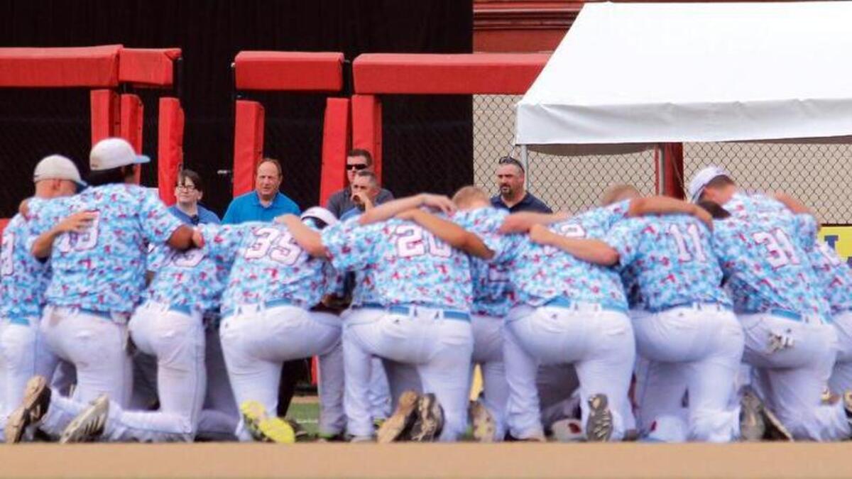 
The Liberal Bee Jays team kneels in prayer near the outfield gate opened for an ambulance to transport Kaiser Carlile to a hospital on Aug. 1. Kaiser, 9, died the next day from injuries sustained when he was struck by a practice swing near the on-deck circle.

