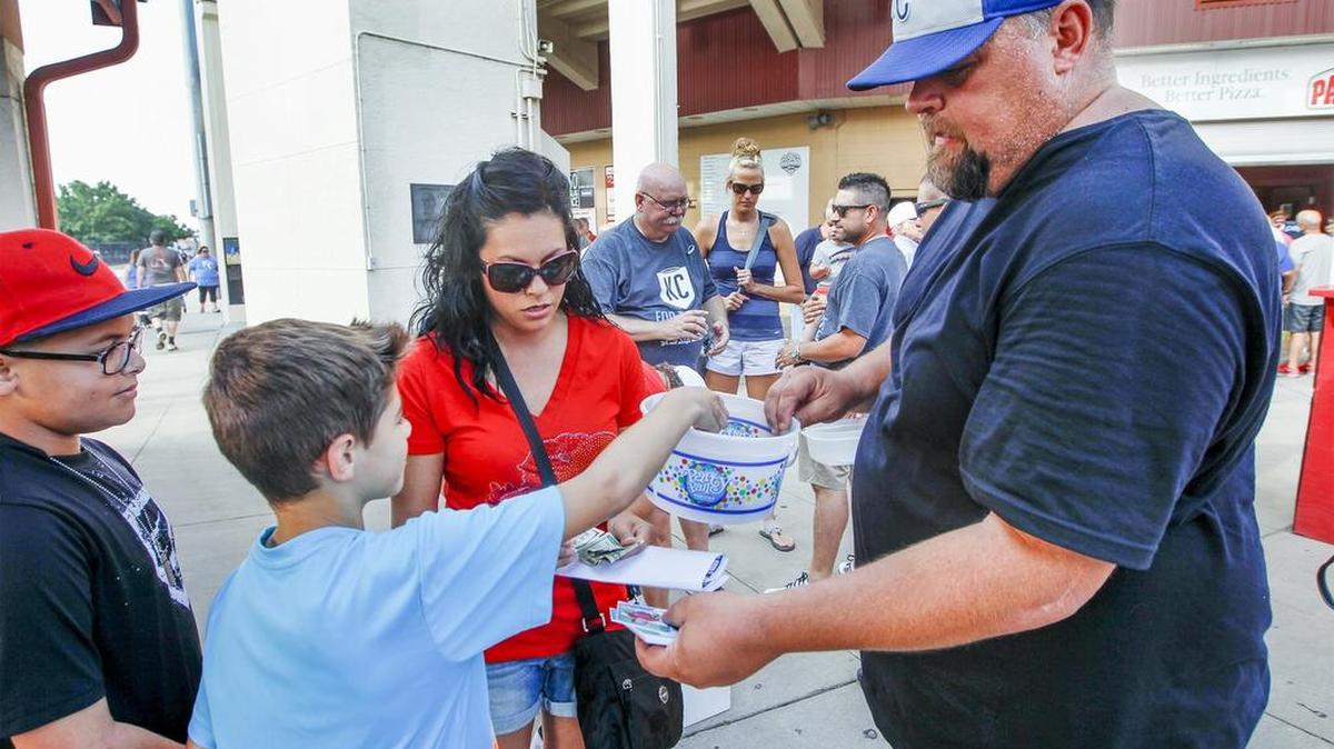 
NBC volunteer Eric Shannon takes donations as he hands out baseball cards of Kaiser Carlile on Tuesday at Lawrence-Dumont Stadium.
