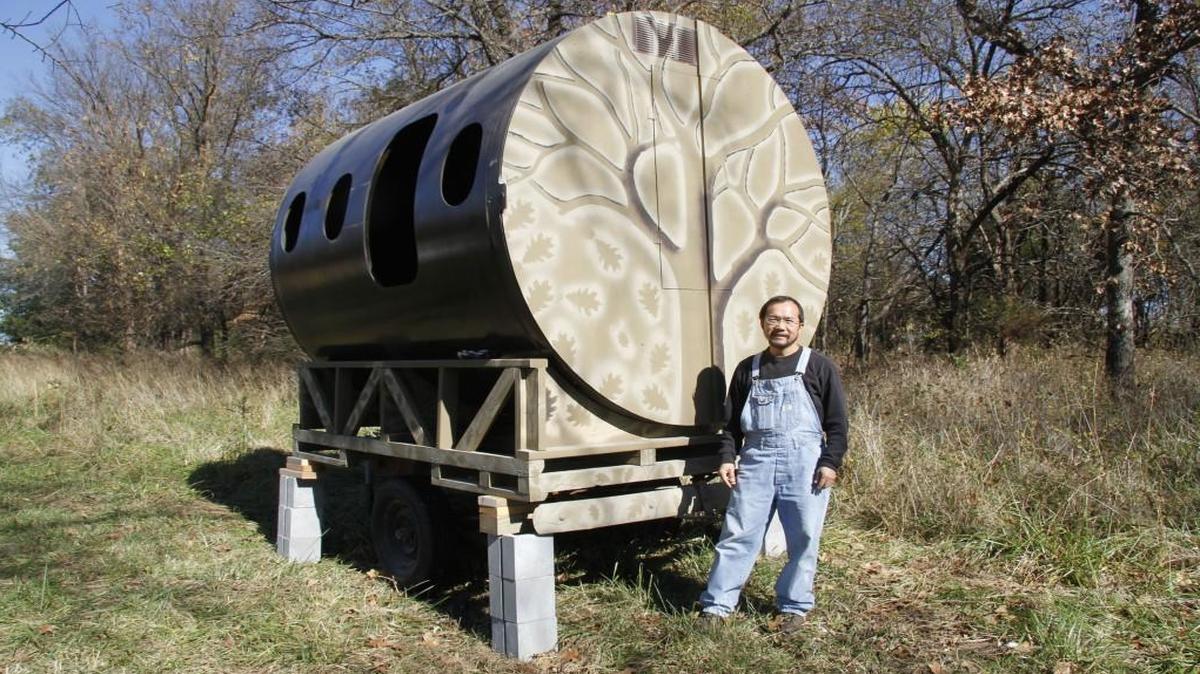 Khoua Thao stands by the wildlife watching/hunting blind he made from a section of airplane fuselage. He considers it a blend of his love of hunting and his job as a mechanical engineer in aviation.