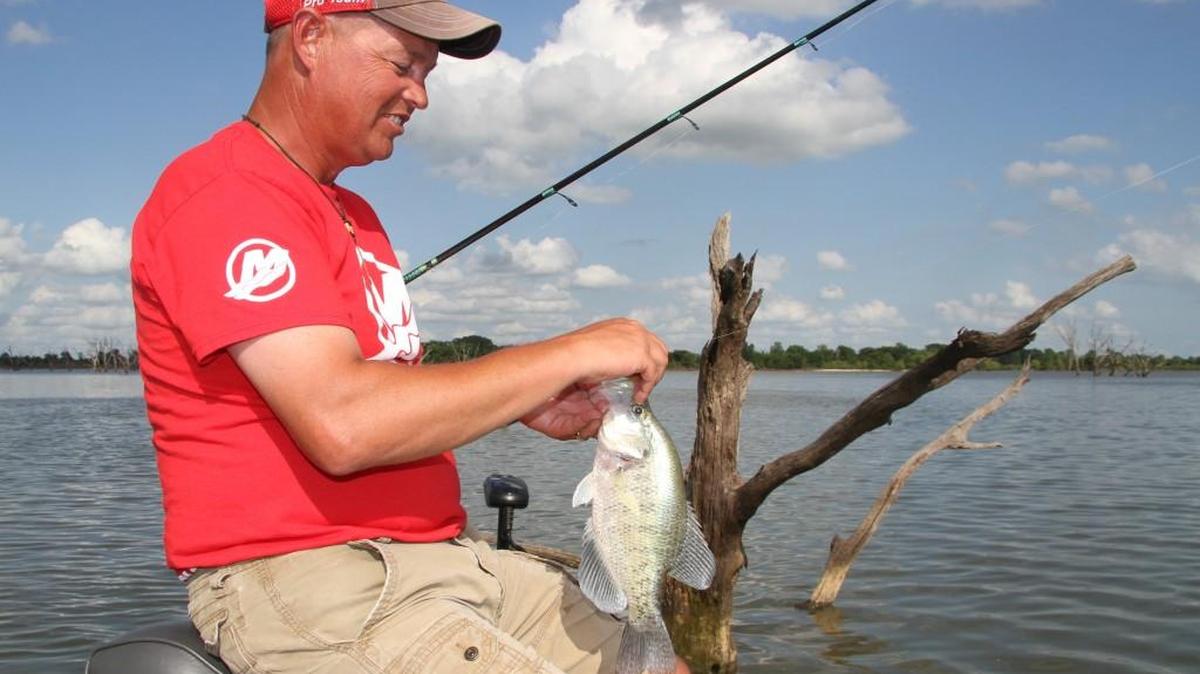 Shane Justice unhooks a 14 1/2-inch crappie he caught fishing around trees Friday evening at El Dorado Reservoir.