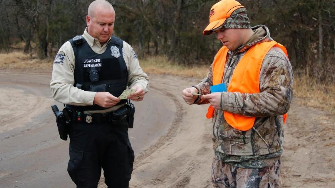 Game warden Jason Barker, left, checks the hunting license and deer permit of Steven Cook last December at the Byron Walker Wildlife Area. Game wardens are using Facebook to help enforce wildlife and private property rights.