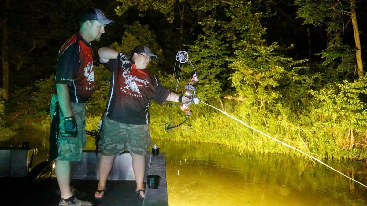 Doug Whitehead, left, watches as his wife, Trisha, takes a shot while bowfishing at Big Hill Reservoir. It’s how the couple spends many nights together.