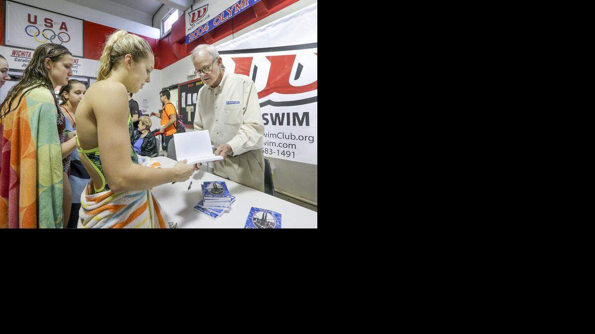 
Wichita Olympian Jeff Farrell hands an autographed copy of his book to Wichita Swim Club member Kendall Kilgore, 17, during his book-signing appearance at the swim club Wednesday. 

