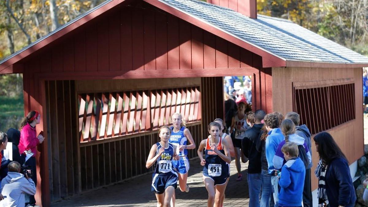 Cross country runners leave the covered bridge on the Rim Rock Farms course during the state championships in 2013.