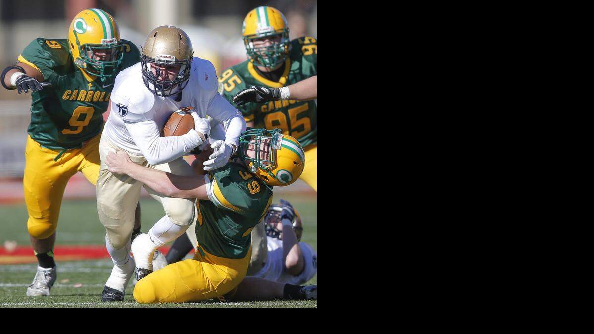 
Carroll's Jarrett Johnson drags down St. Thomas Aquinas' Ben Ewing during the first quarter in Pittsburg on Saturday. Carroll went on to win 39-7.
